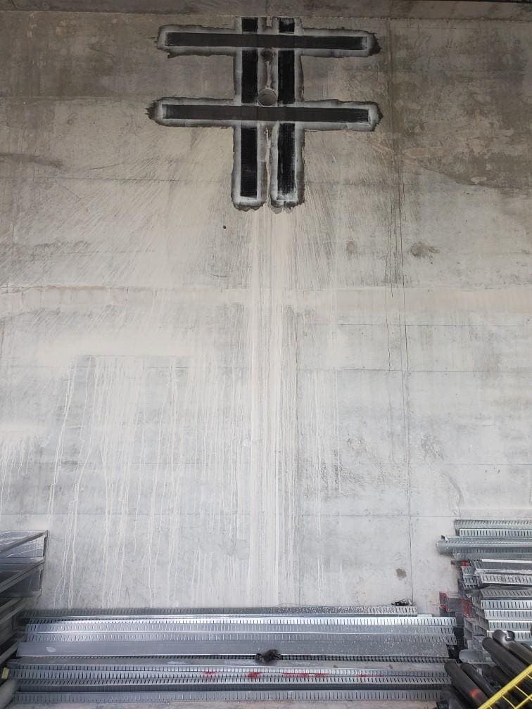 Hash-pattern black strips around a small penetration in a concrete wall.