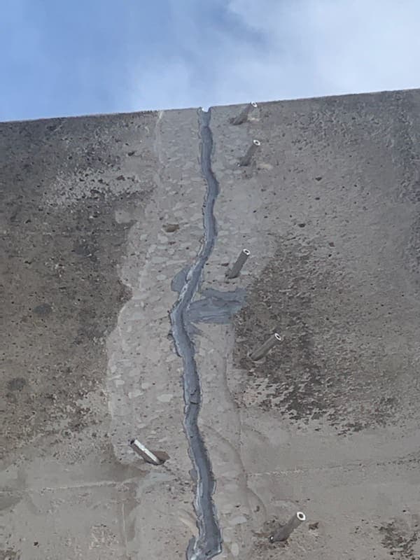 Looking up a concrete wall at a sealed vertical crack with injection ports.
