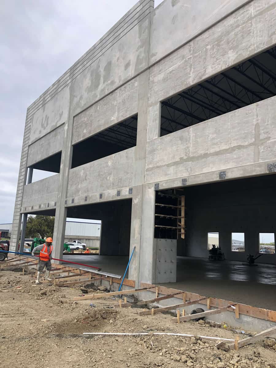 Three-story concrete tilt-up building exterior with site work.