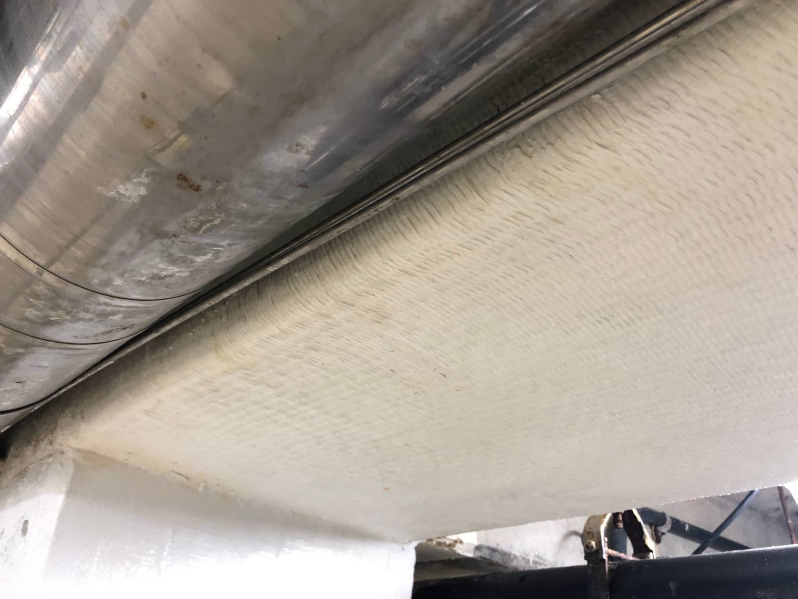 Painted concrete beam showing the fabric texture of a bonded composite wrap.