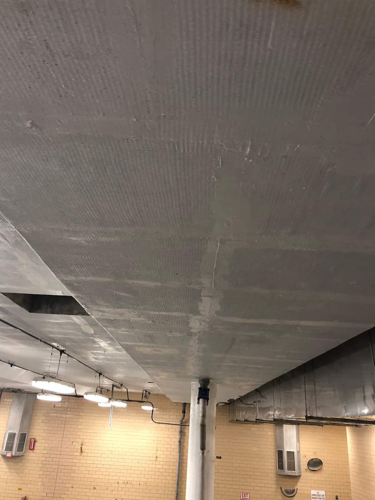 Wide painted beam soffit with composite wrap texture running toward a tiled wall.