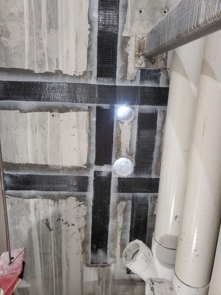 Carbon fiber strips around two penetrations near PVC pipes.