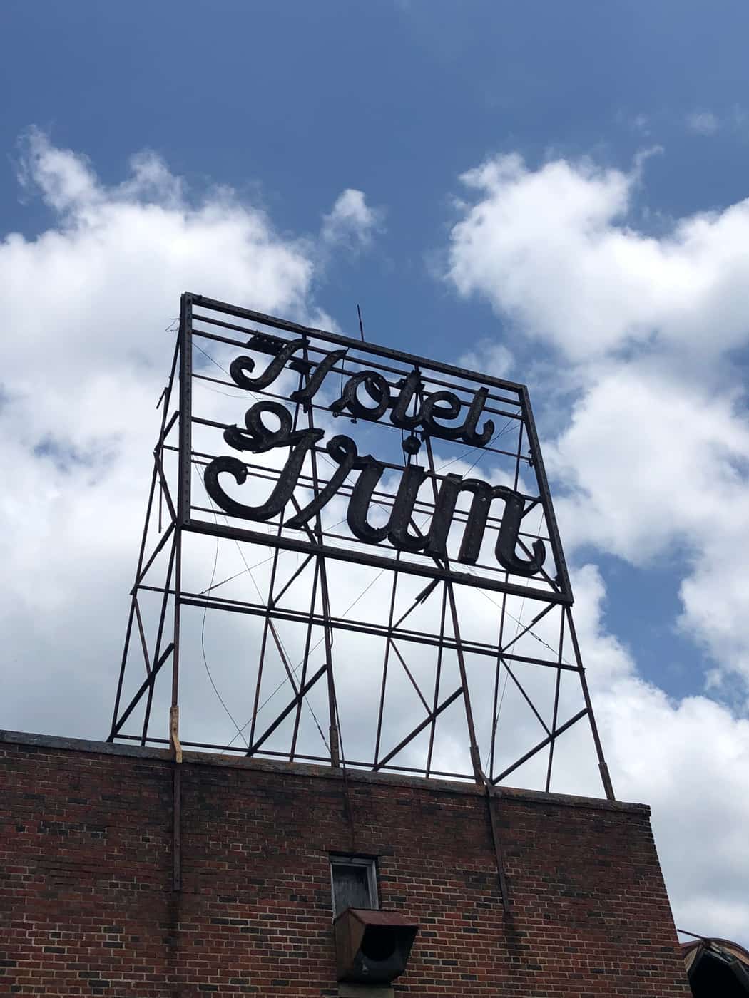 Rooftop script sign reading Hotel Grim on a steel frame above a brick parapet.
