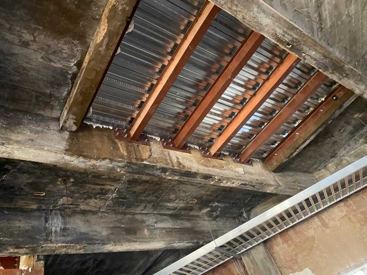New steel beams and galvanized metal deck infilling an opening in concrete framing.