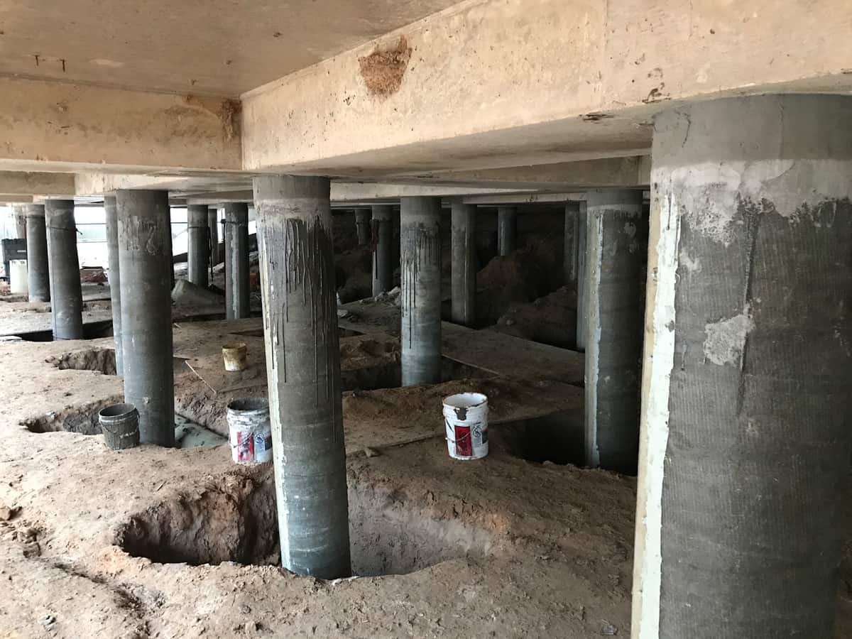 Rows of round piles fitted with fiberglass jackets beneath a concrete deck.