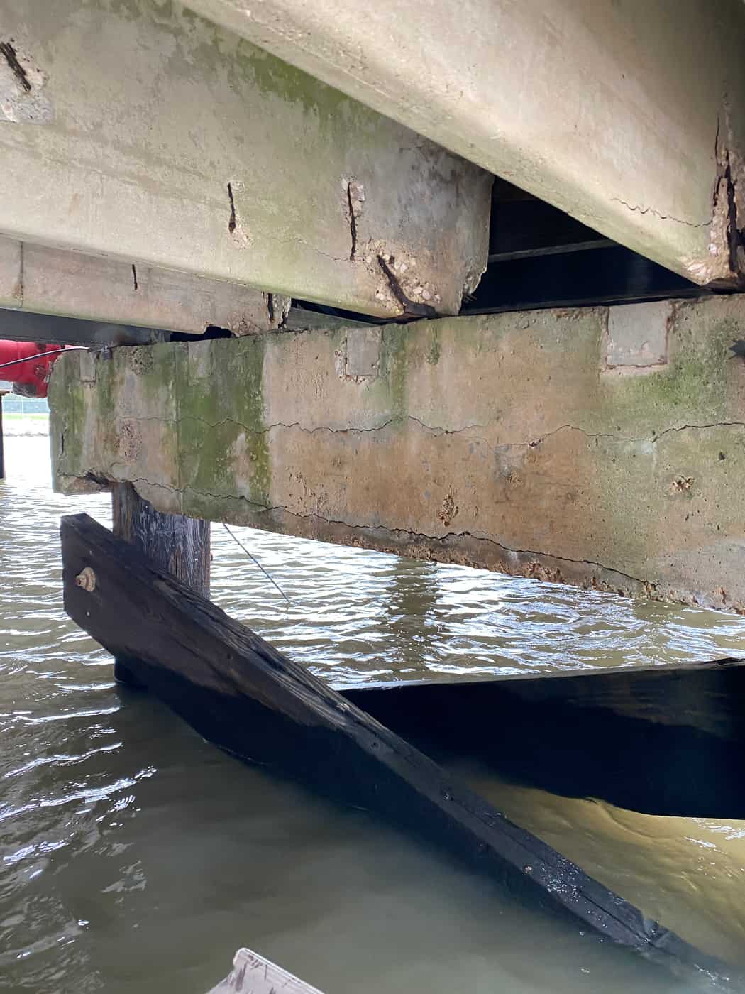 Cracked concrete pile cap with timber bracing under dock deck girders.