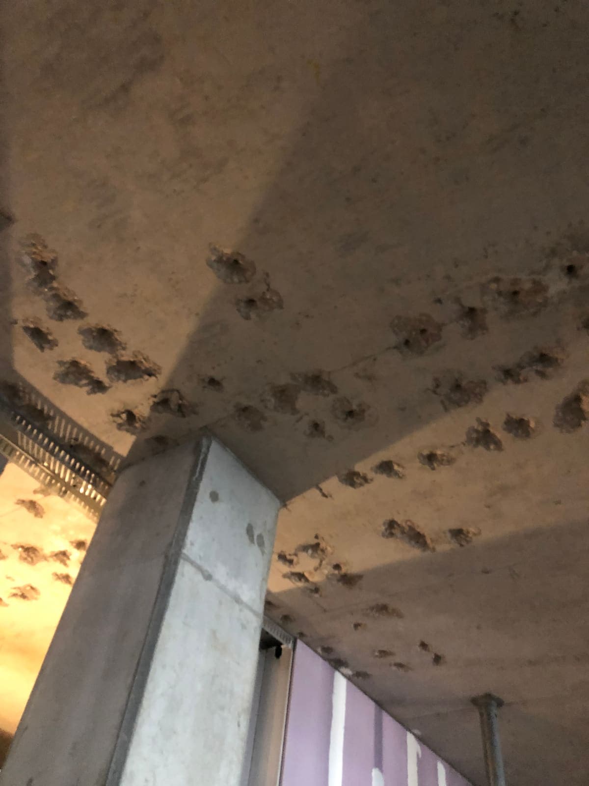 Slab underside with patched holes radiating around a concrete column head.