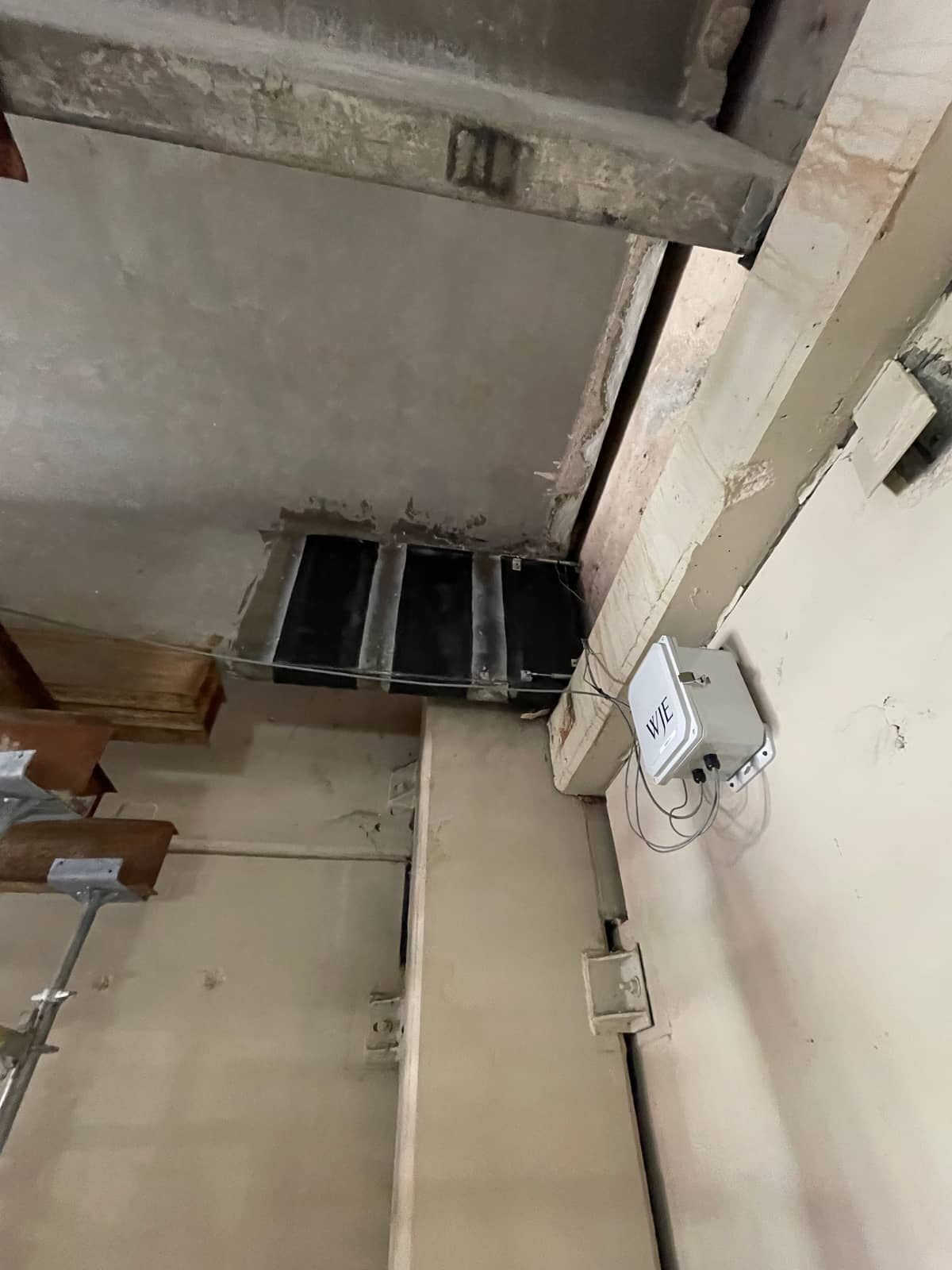 Carbon fiber strips at a concrete beam end next to wall-mounted junction boxes.