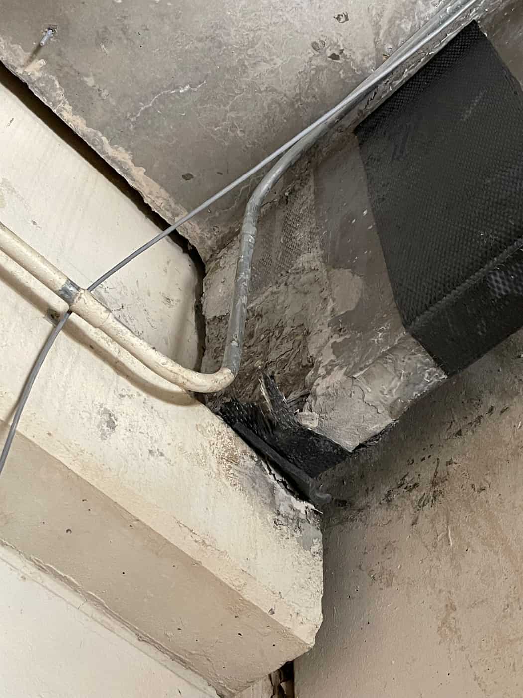Carbon fiber wrap on a concrete beam end with a conduit crossing in front.