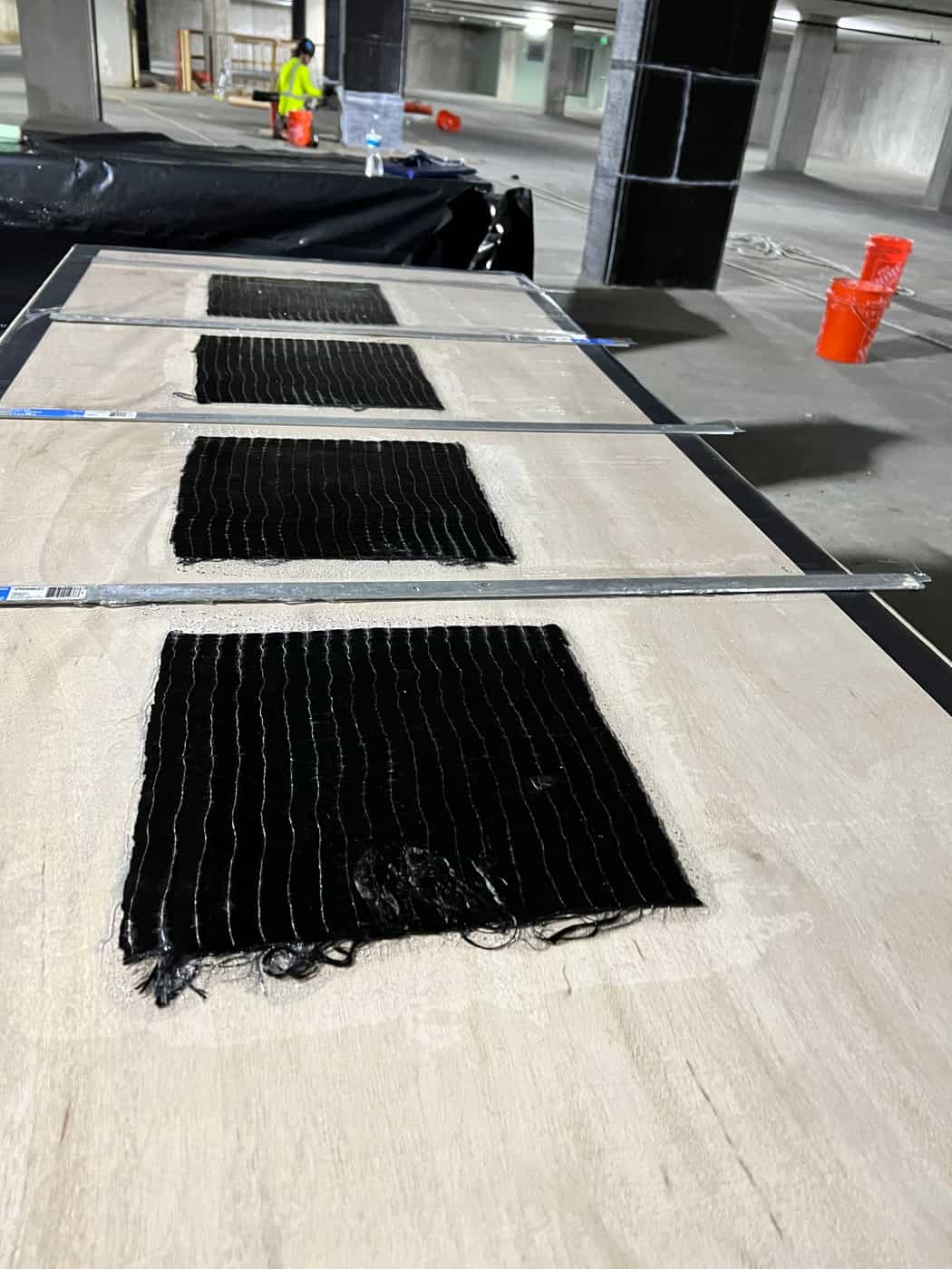Carbon fiber sheets laid out and saturated on a plastic-covered work table.