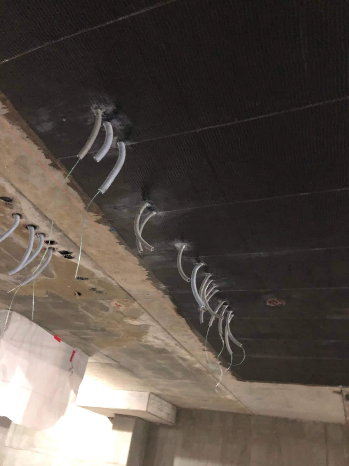 Carbon fiber on a slab underside with splayed fiber anchors at a beam edge.