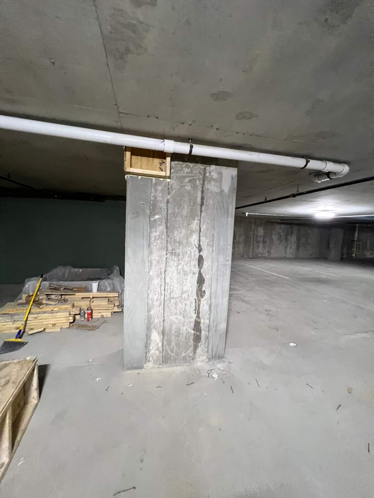 Concrete column with a vertical patched strip prepared for repair.