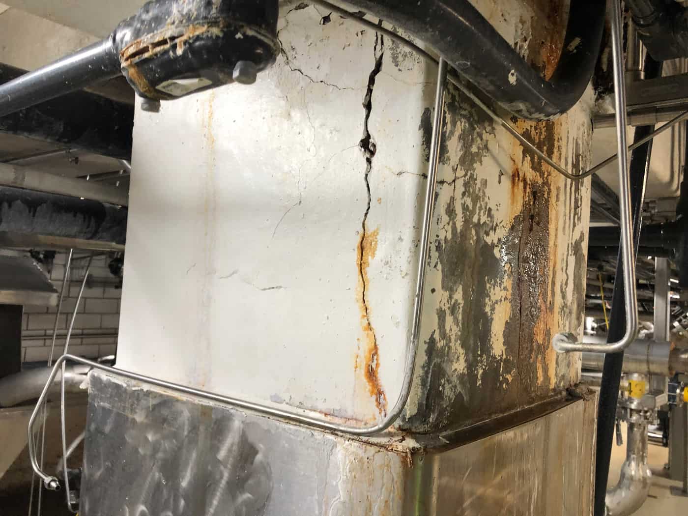 Column with a vertical rust-stained crack above stainless base cladding.