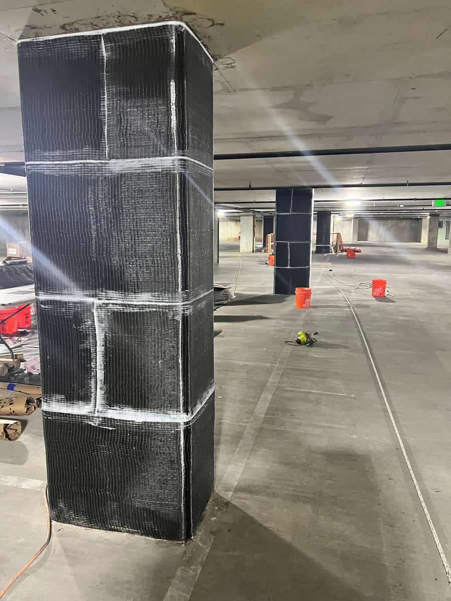 Rectangular column fully wrapped in carbon fiber with white epoxy seams.
