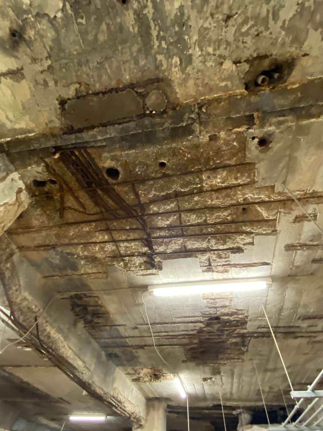 Heavily spalled slab soffit with exposed bars and beams.