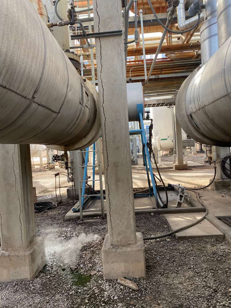 Concrete support columns on footings between insulated pipes.