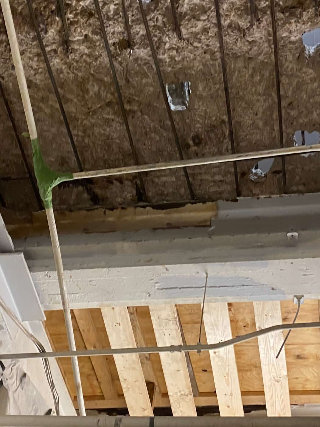 Deteriorated slab underside with exposed rebar and timber shoring below.