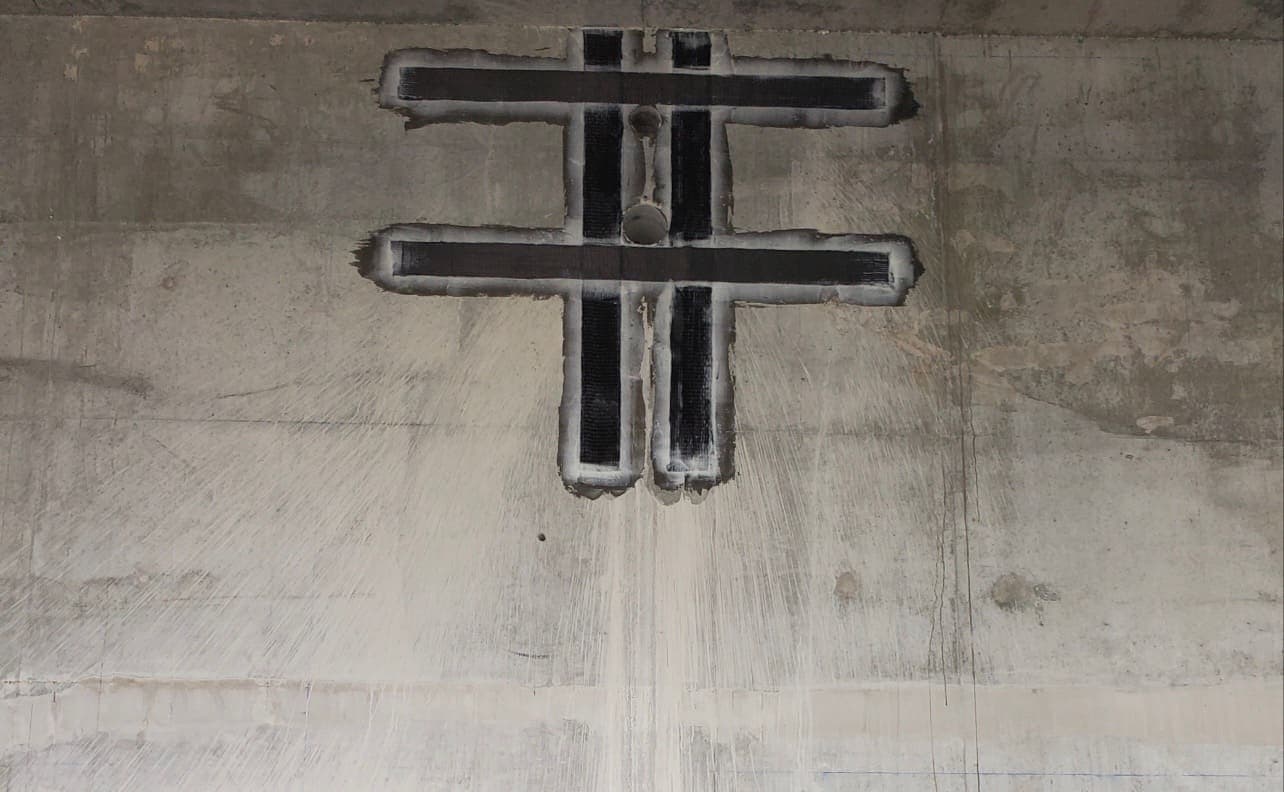 Close view of hash-pattern black composite strips around a penetration in a concrete wall.