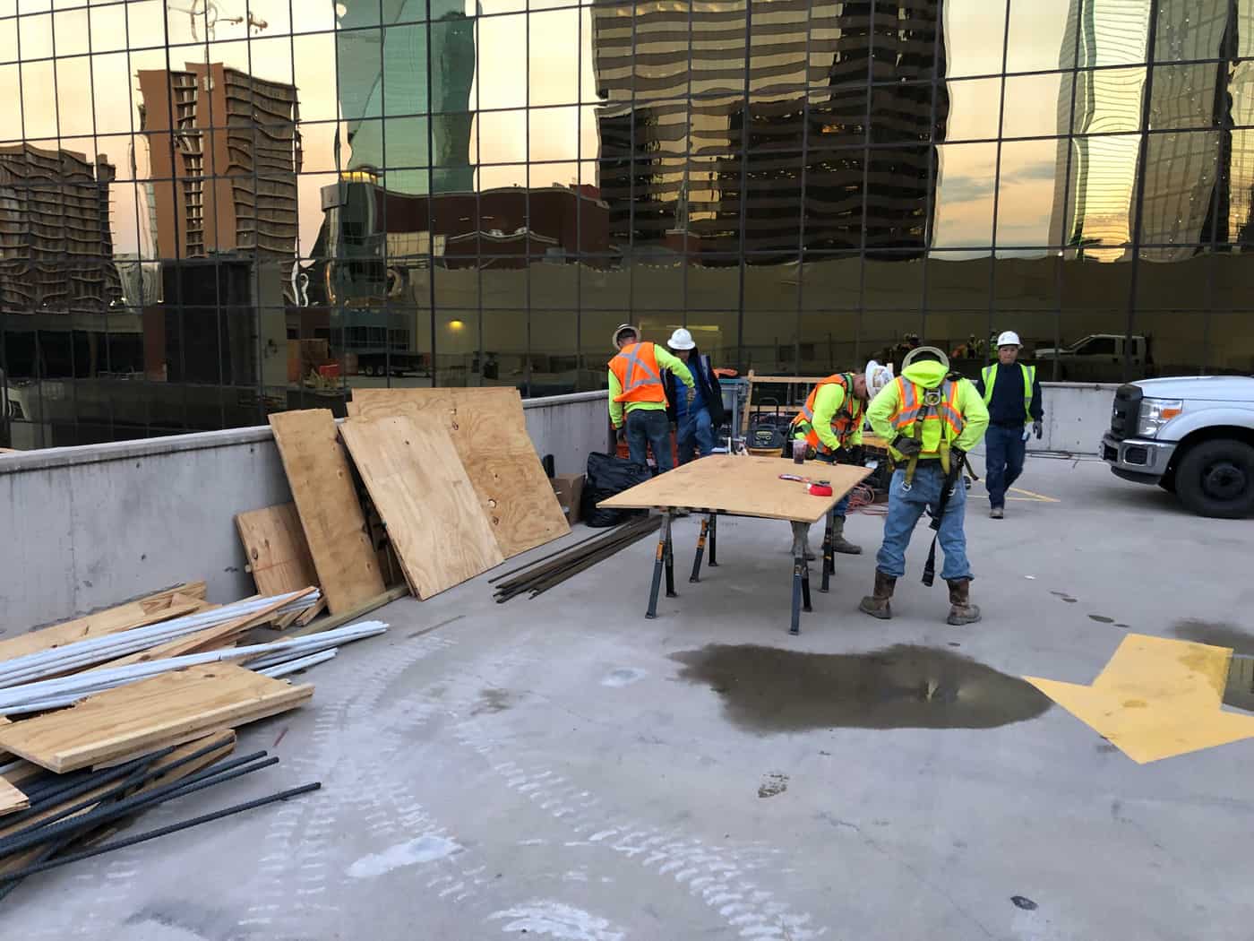 Workers cutting plywood forms on a rooftop deck.