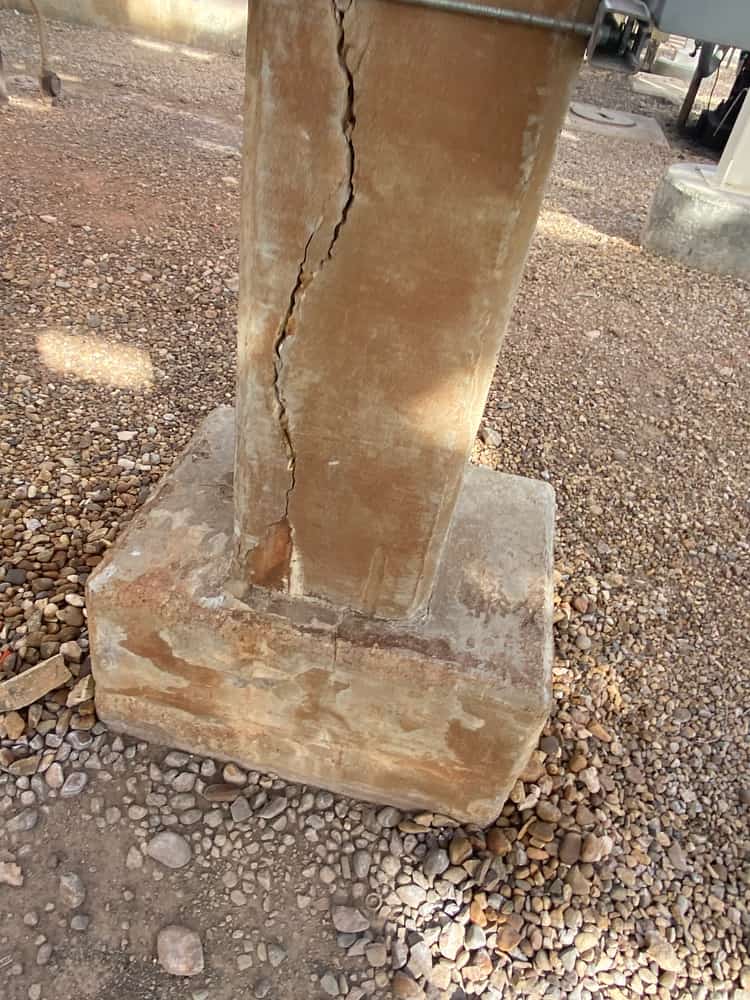 Column base on a pedestal with a long vertical crack running into the pedestal.